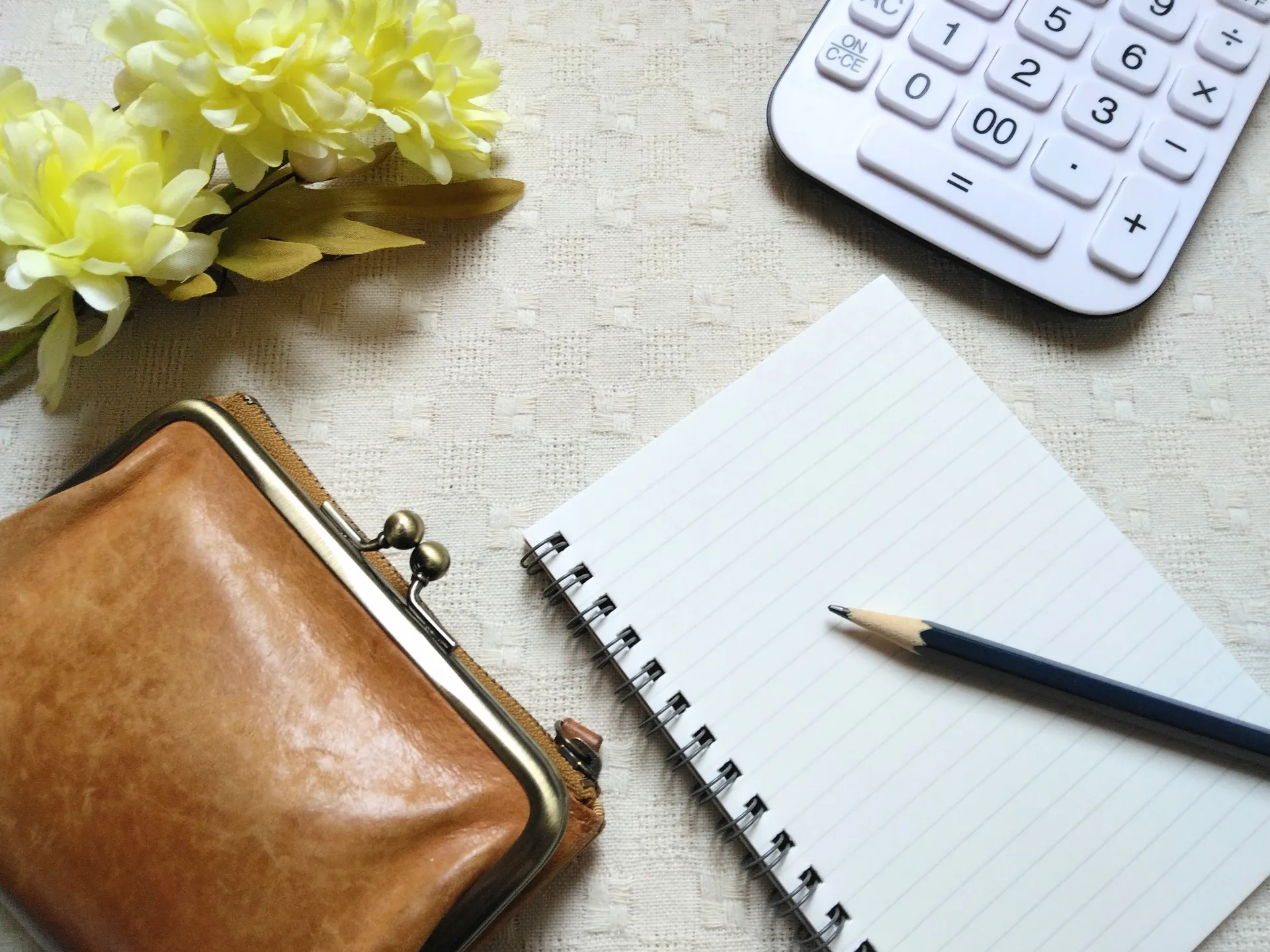 筆記用具と財布、電卓がテーブルに置かれた画像