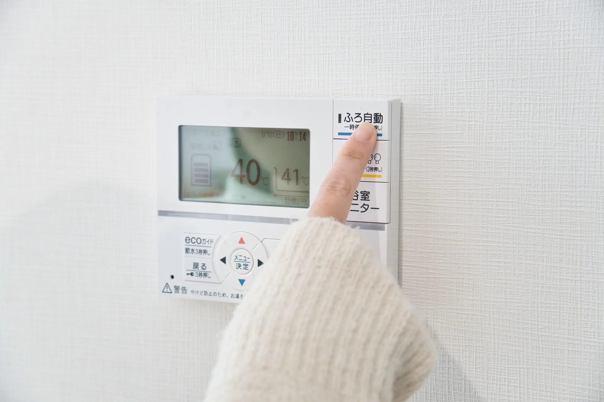 女性が給湯器のリモコンを操作する様子